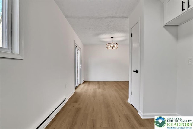 182 Maxatawny Dr, Coolbaugh Twp, PA 18347 - hallway with a baseboard heating unit, light wood-style floors, a chandelier, a textured ceiling, and plenty of natural light