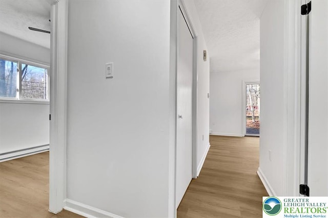 182 Maxatawny Dr, Coolbaugh Twp, PA 18347 - hallway featuring plenty of natural light, wood finished floors, a baseboard heating unit, and a textured ceiling