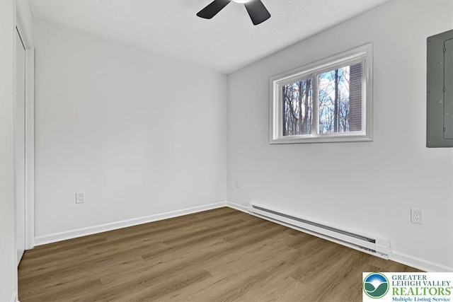 182 Maxatawny Dr, Coolbaugh Twp, PA 18347 - empty room featuring a baseboard heating unit, wood finished floors, a ceiling fan, and electric panel