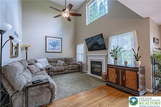 2877 Hope Ridge Dr, Bethlehem Twp, PA 18045 - living room with high vaulted ceiling, a ceiling fan, a tiled fireplace, and wood finished floors