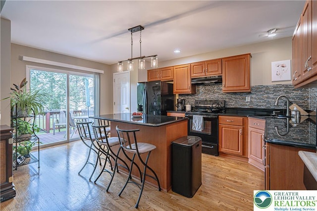 2877 Hope Ridge Dr, Bethlehem Twp, PA 18045 - kitchen with black appliances, ventilation hood, dark countertops, and a breakfast bar