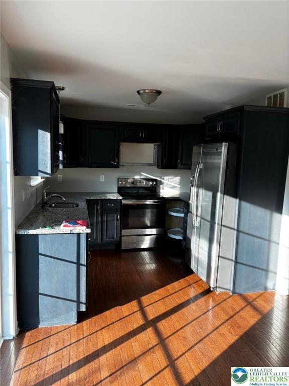 4954 Coatbridge Ln, Lehigh Twp, PA 18088 - kitchen featuring stainless steel appliances, dark cabinets, dark wood-style floors, and light countertops