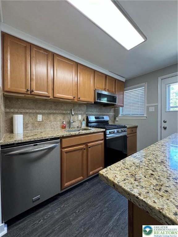 449 E Garrison St, Bethlehem City, PA 18018 - kitchen with stainless steel appliances, dark wood finished floors, backsplash, and brown cabinetry