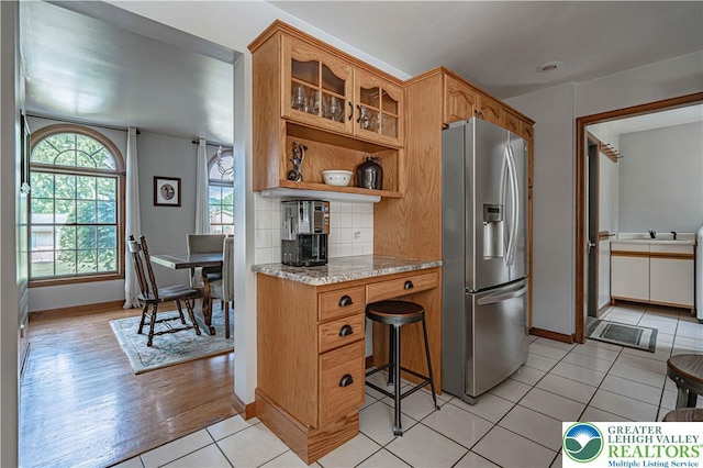 2029 Amherst Dr, Lower Saucon Twp, PA 18015 - kitchen with stainless steel refrigerator with ice dispenser, decorative backsplash, glass insert cabinets, light stone counters, and open shelves
