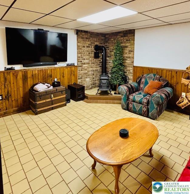 2734 Old Bethlehem Pike, Milford Twp, PA 18951 - living area with wainscoting, a wood stove, a paneled ceiling, and tile patterned floors
