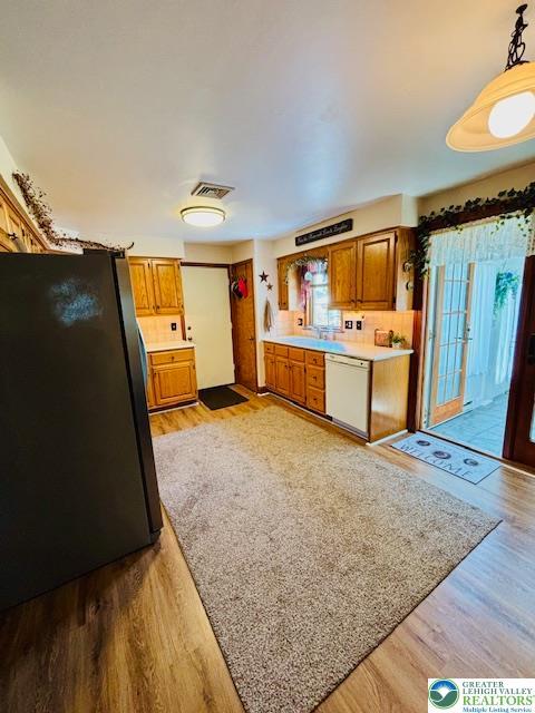2734 Old Bethlehem Pike, Milford Twp, PA 18951 - kitchen with freestanding refrigerator, white dishwasher, light wood-type flooring, and brown cabinets