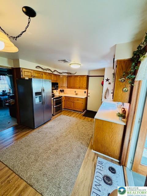 2734 Old Bethlehem Pike, Milford Twp, PA 18951 - kitchen with stainless steel appliances, brown cabinetry, light wood-type flooring, and light countertops