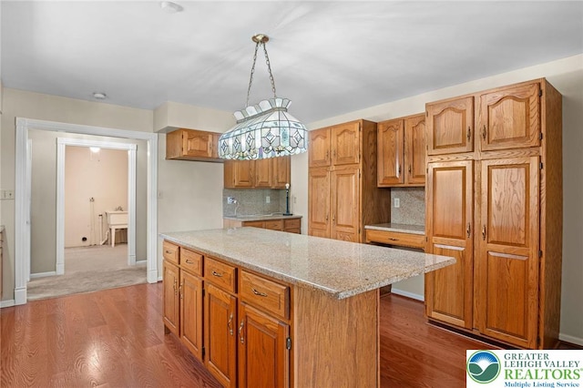 242 Schoeneck Ave, Nazareth Boro, PA 18064 - kitchen featuring a center island, decorative backsplash, wood finished floors, light stone countertops, and brown cabinetry