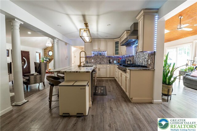 1555 Longleaf Dr, Chestnuthill Twp, PA 18330 - kitchen with cream cabinets, wall chimney range hood, stainless steel gas cooktop, ornate columns, and recessed lighting