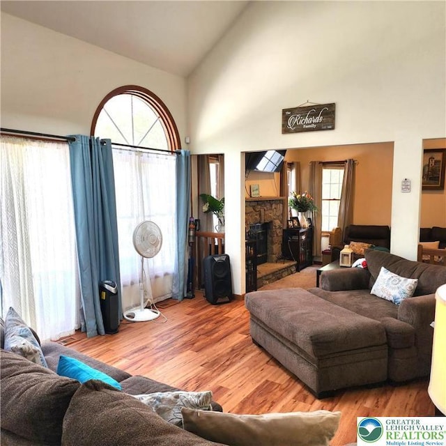 408 Sassafrass Way, Jackson Twp, PA 18360 - living room featuring wood finished floors, high vaulted ceiling, a stone fireplace, and plenty of natural light