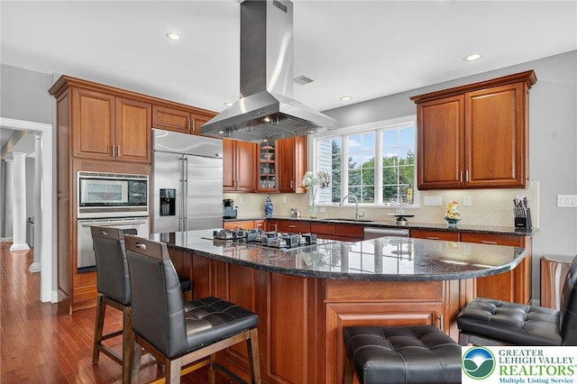 4508 Homestead Dr, Lower Nazareth Twp, PA 18064 - kitchen with island exhaust hood, built in appliances, dark wood-type flooring, brown cabinets, and recessed lighting