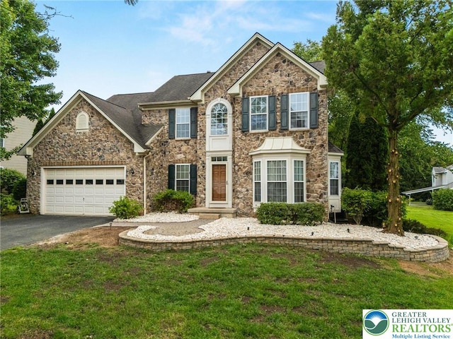 232 S 33rd St, South Whitehall Twp, PA 18104 - view of front facade with stone siding, asphalt driveway, a garage, a front yard, and roof with shingles
