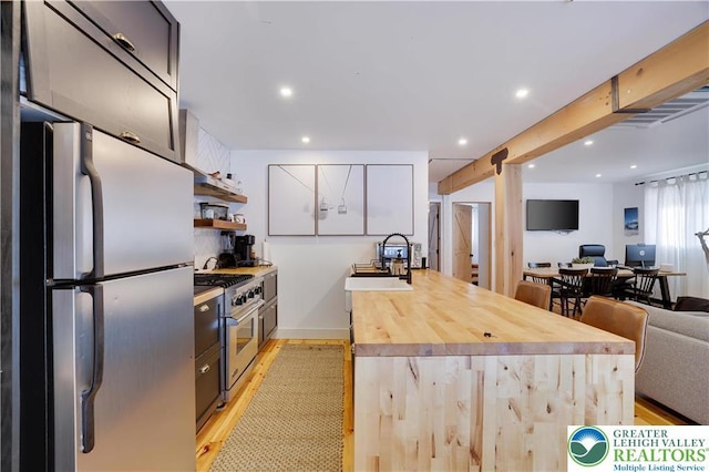 9379 Fairmount, Coolbaugh Twp, PA 18466 - kitchen featuring appliances with stainless steel finishes, light wood-type flooring, open floor plan, a peninsula, and wood counters