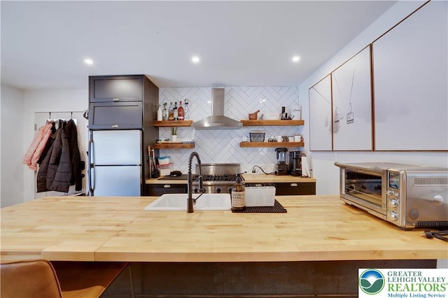 9379 Fairmount, Coolbaugh Twp, PA 18466 - kitchen featuring wall chimney range hood, freestanding refrigerator, wood counters, open shelves, and decorative backsplash