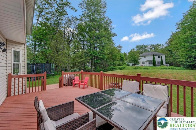 5117 Hounds Ear Rd, Coolbaugh Twp, PA 18466 - wooden terrace featuring a trampoline, outdoor dining area, a lawn, and view of wooded area