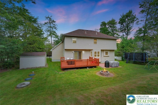 5117 Hounds Ear Rd, Coolbaugh Twp, PA 18466 - rear view of house with a trampoline, a fire pit, a deck, a storage unit, and a yard
