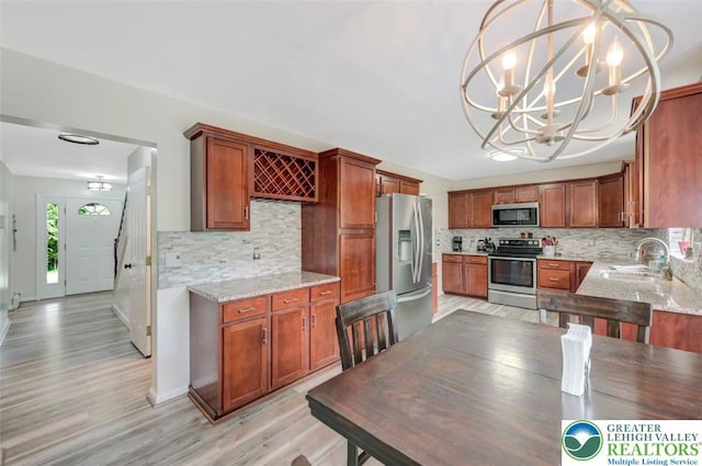 5117 Hounds Ear Rd, Coolbaugh Twp, PA 18466 - kitchen featuring stainless steel appliances, a chandelier, decorative backsplash, light wood-type flooring, and light stone counters