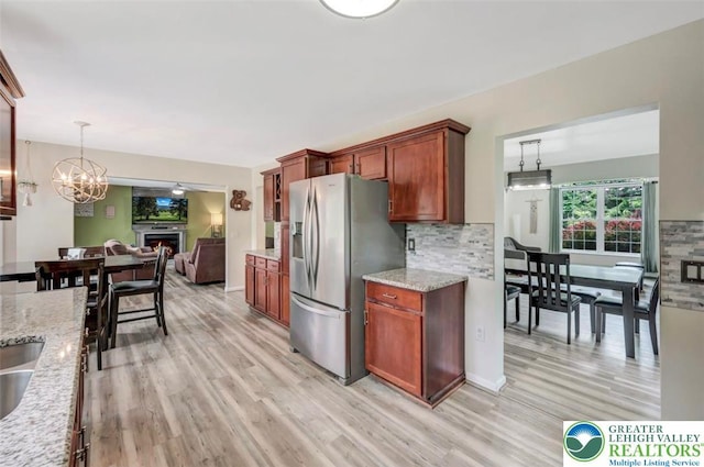 5117 Hounds Ear Rd, Coolbaugh Twp, PA 18466 - kitchen featuring stainless steel refrigerator with ice dispenser, light wood finished floors, backsplash, and light stone countertops