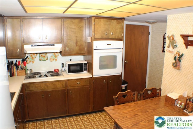 1321 Bushkill Center Rd, Bushkill Twp, PA 18091 - kitchen with white appliances, under cabinet range hood, light countertops, and wallpapered walls