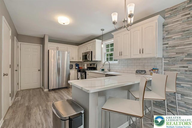 5 Flagstone Ln, East Stroudsburg, PA 18302 - kitchen featuring appliances with stainless steel finishes, light wood-style floors, a peninsula, tasteful backsplash, and light countertops