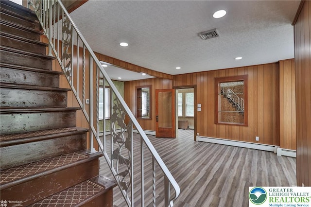 1911 Echo Rd, North Whitehall Twp, PA 18080 - stairs with baseboard heating, wood finished floors, a textured ceiling, wooden walls, and radiator heating unit