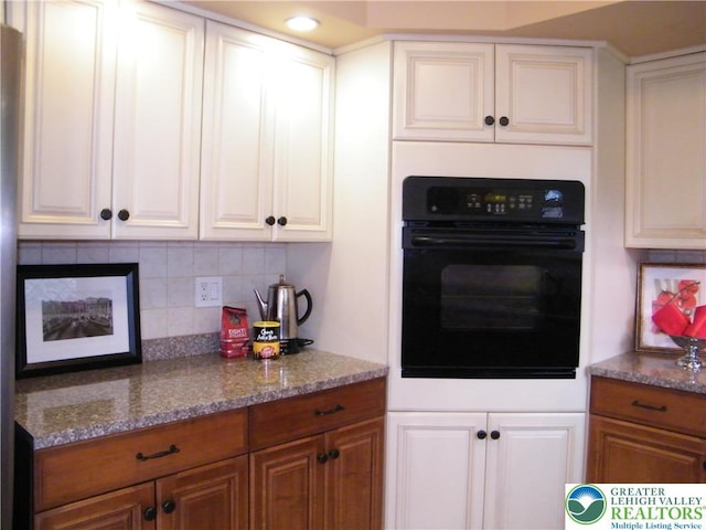 3415 Kathleen Ave, Salisbury Twp, PA 18103 - kitchen featuring black oven, backsplash, brown cabinetry, stone countertops, and white cabinetry