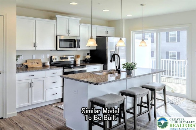 3229 Tepes Dr Lot 138, Allen Twp, PA 18067 - kitchen with stainless steel appliances, a breakfast bar, light wood-type flooring, a center island with sink, and white cabinets