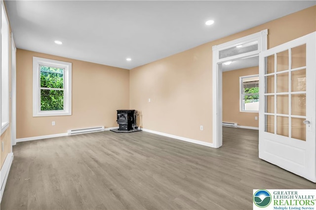 5734 Rte 873, North Whitehall Twp, PA 18078 - empty room with a baseboard radiator, a wood stove, wood finished floors, plenty of natural light, and recessed lighting