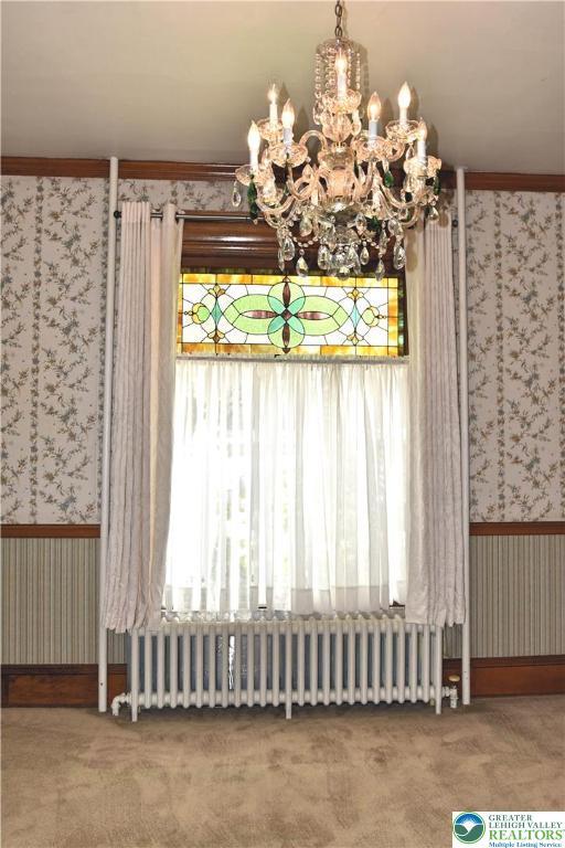 107 N Schanck Ave, Pen Argyl Boro, PA 18072 - unfurnished dining area featuring wallpapered walls, radiator, carpet, and a chandelier