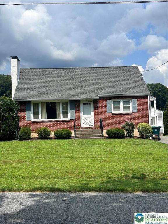 2653 Woodlawn Ave, Palmer Twp, PA 18045 - view of front of home with a front yard, a chimney, brick siding, and a shingled roof