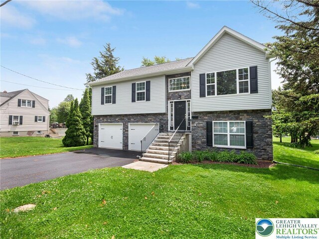 317 Fairview Ave, Wind Gap Boro, PA 18091 - bi-level home featuring an attached garage, asphalt driveway, a front yard, and stone siding