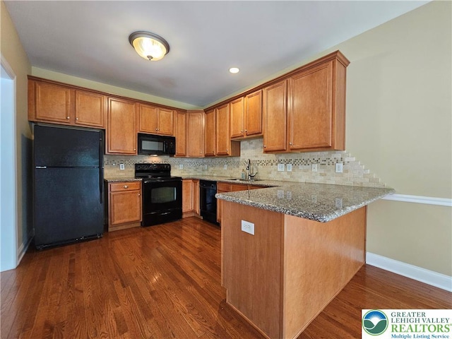 312 Maple Ct, Alburtis Boro, PA 18011 - kitchen with black appliances, a peninsula, stone counters, brown cabinetry, and dark wood-style floors
