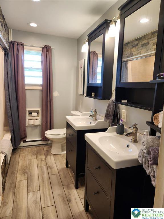 2840 Roosevelt St, Bethlehem Twp, PA 18020 - full bath featuring wood finished floors, two vanities, a baseboard radiator, a shower with shower curtain, and recessed lighting