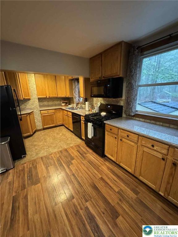 15 Hiawatha Trl, Penn Forest Twp, PA 18210 - kitchen featuring black appliances, backsplash, wood finished floors, brown cabinetry, and light countertops