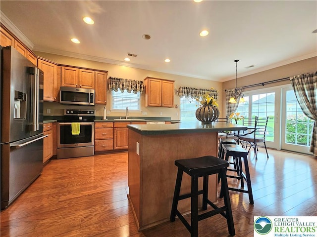 15 Devonshire Dr, Palmer Twp, PA 18045 - kitchen with stainless steel appliances, ornamental molding, a kitchen island, light wood-style floors, and a kitchen breakfast bar