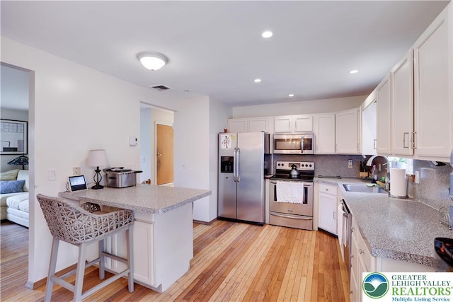303 Lakefield Ter, Jackson Twp, PA 18360 - kitchen with appliances with stainless steel finishes, white cabinetry, a peninsula, light wood finished floors, and light countertops