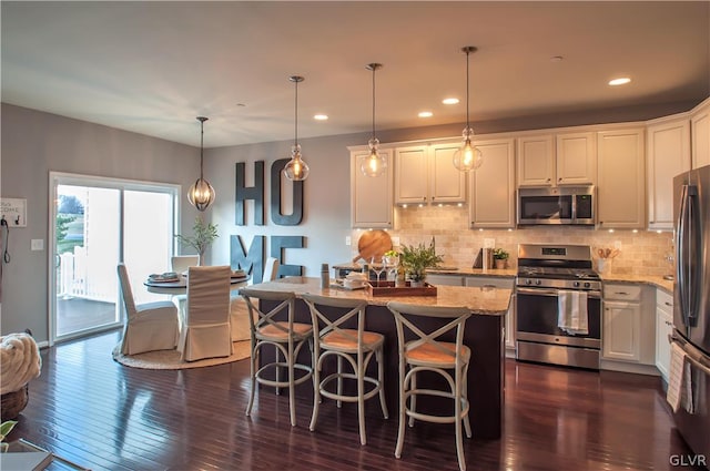 kitchen with white cabinetry, light stone counters, dark hardwood / wood-style floors, stainless steel appliances, and pendant lighting