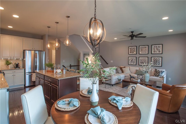 dining area with dark wood-type flooring and ceiling fan with notable chandelier