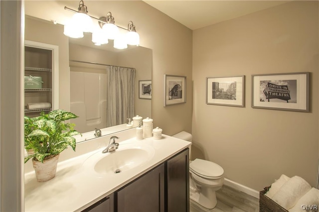 bathroom featuring hardwood / wood-style flooring, vanity, toilet, and curtained shower