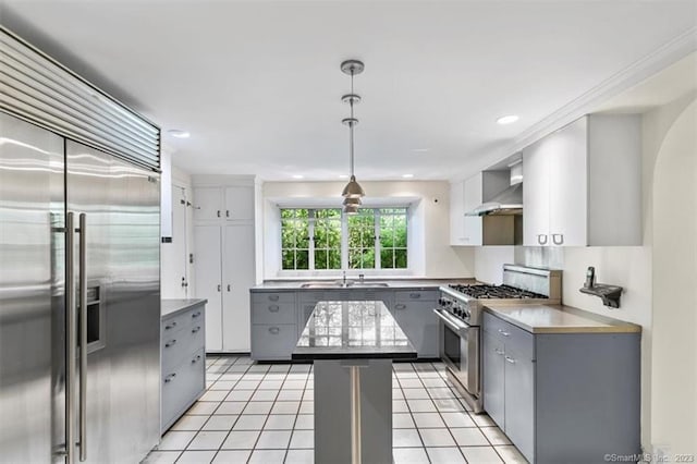 kitchen with light tile floors, gray cabinetry, high end appliances, wall chimney exhaust hood, and sink