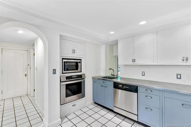 kitchen with stainless steel appliances, light tile flooring, white cabinetry, and sink