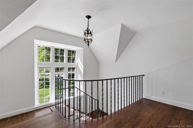 staircase with a notable chandelier, lofted ceiling, and dark hardwood / wood-style flooring