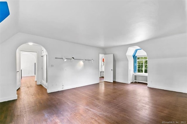 bonus room with vaulted ceiling, dark hardwood / wood-style floors, and radiator