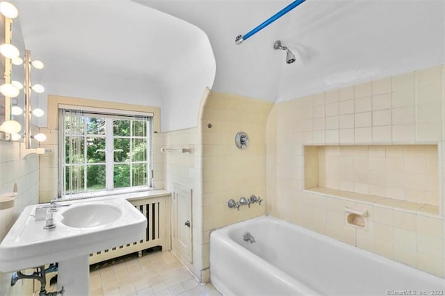 bathroom with tiled shower / bath combo, tile flooring, sink, and tile walls