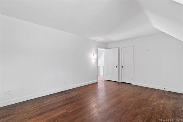 spare room with dark hardwood / wood-style flooring and vaulted ceiling