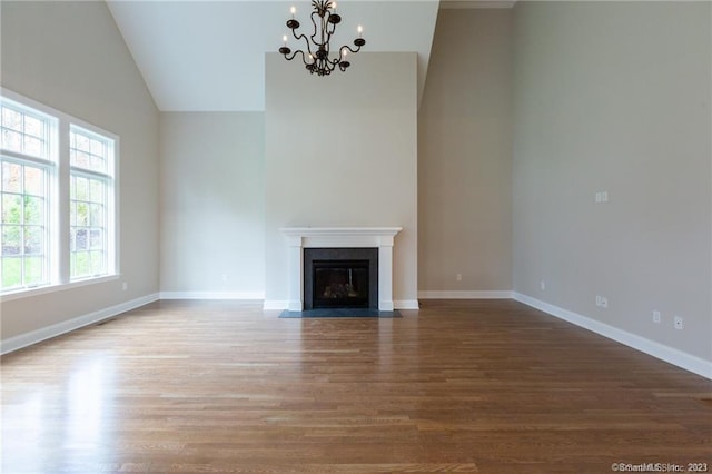 unfurnished living room with an inviting chandelier, dark wood-type flooring, and high vaulted ceiling