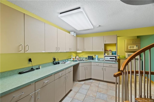 kitchen with sink, light tile floors, and a textured ceiling