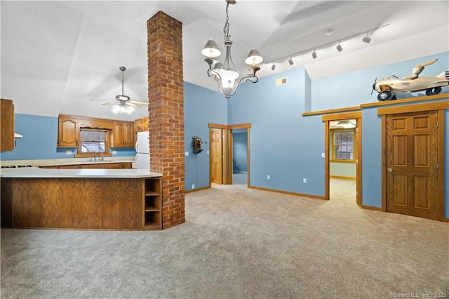 kitchen with decorative light fixtures, light colored carpet, brick wall, rail lighting, and lofted ceiling