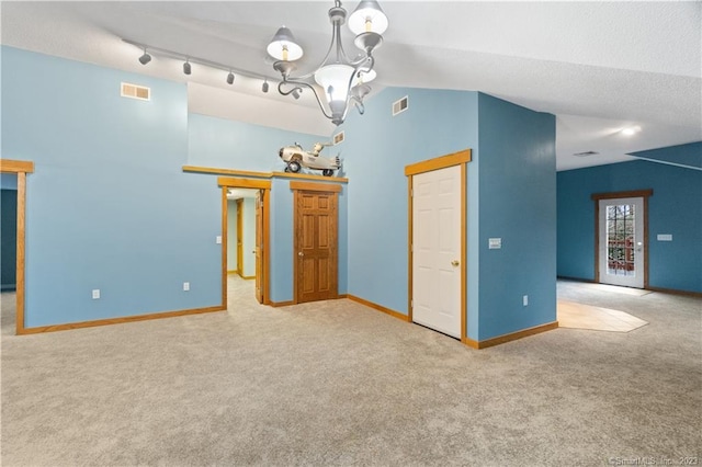 interior space featuring a textured ceiling, track lighting, lofted ceiling, and a chandelier