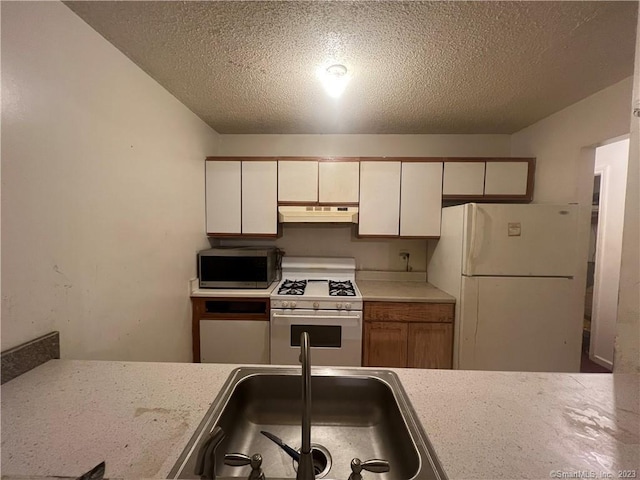 kitchen with sink, white appliances, and a textured ceiling